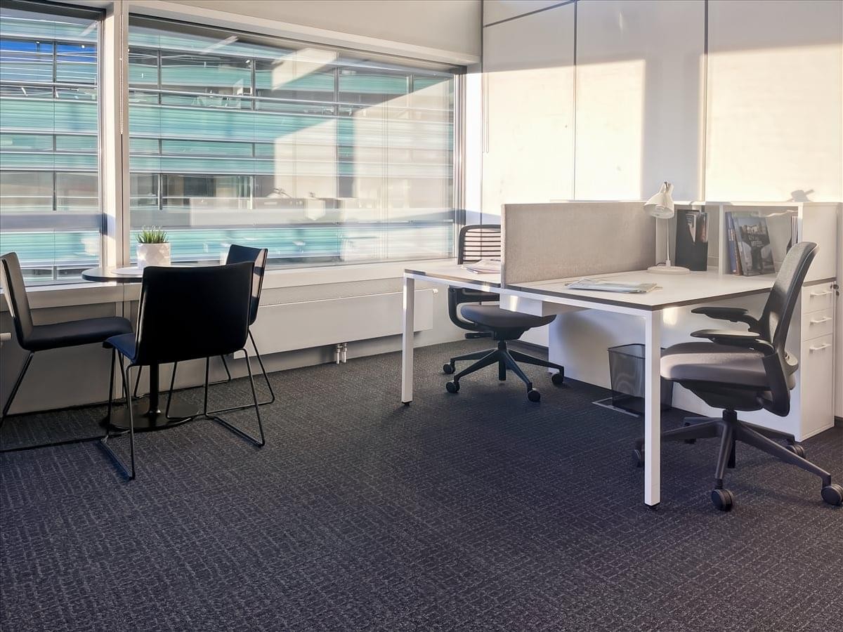 Contemporary office suite at Konstitucijos av. 21A with white desks and dark carpeting.