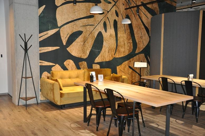 Lounge area with a yellow velvet sofa and a large botanical leaf wall mural.