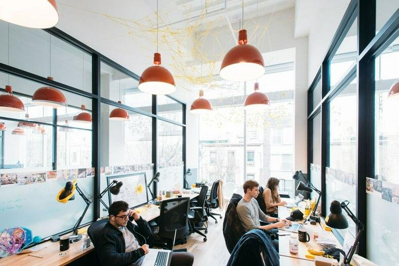 Spacious open-plan workspace at Krucza 50, Warsaw, Poland with rows of desks and modern red pendant lighting.