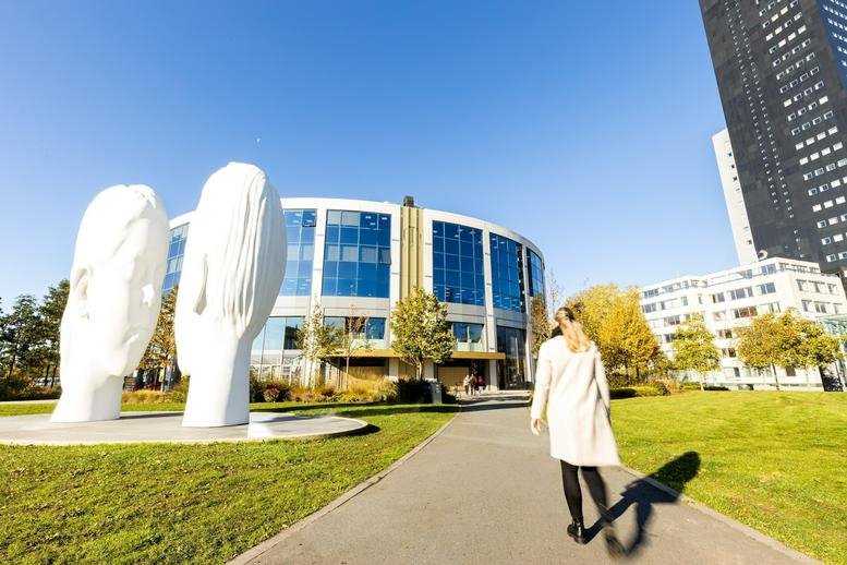 Exterior view of the curved glass facade at Lange Marktstraat 1 with white modern sculptures.