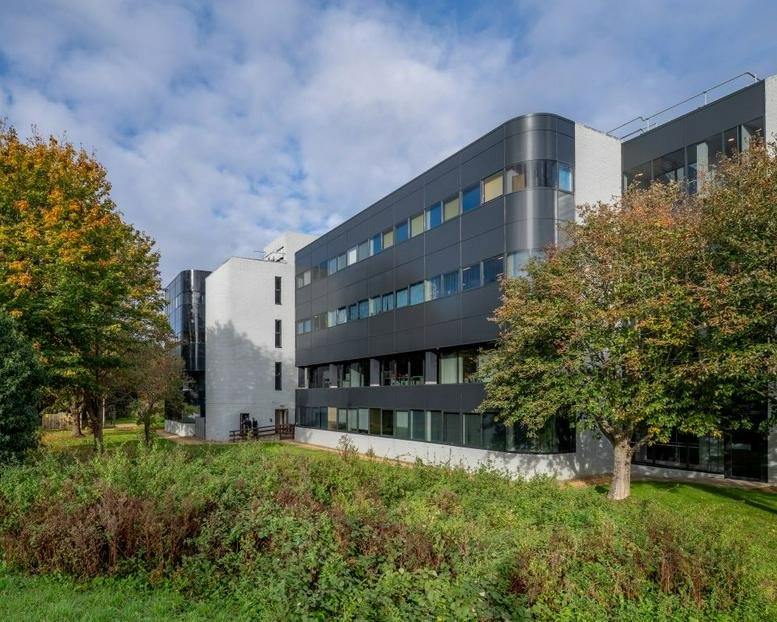 Modern exterior of Langstone Gate with glass and black facade panels surrounded by trees.
