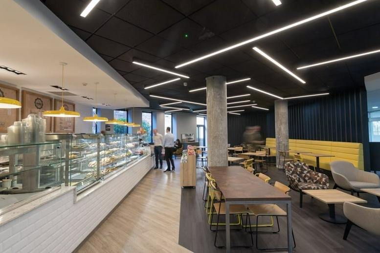 Spacious communal cafe area at 27 Middleborough, Colchester with modern strip lighting and cake display.