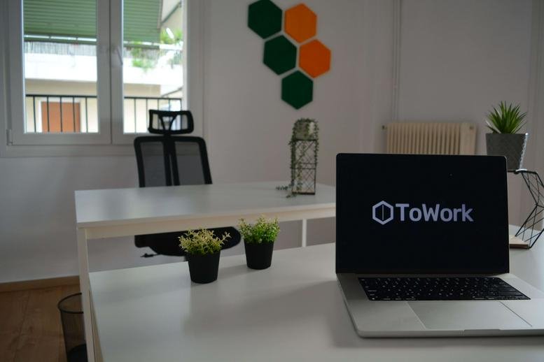 Modern office interior with white desks, green plants, and colorful hexagonal wall acoustic panels.