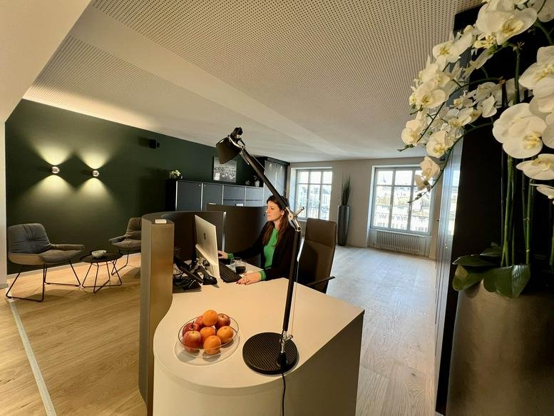 Reception area at Limmatquai 4, Zürcherhof, featuring a modern desk, green feature wall, and floral arrangement.
