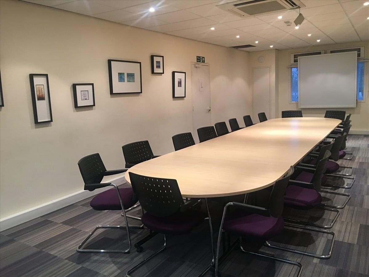Spacious boardroom at Linford Forum with a long wooden table and framed wall art.