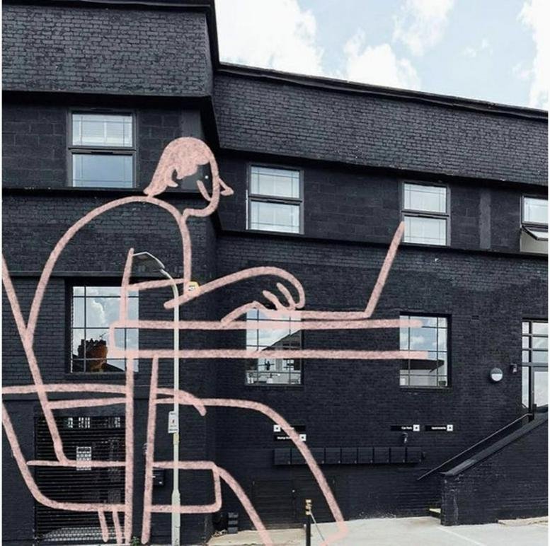 Exterior view of the dark brick facade at Canal House with a large modern line-art mural of a person.