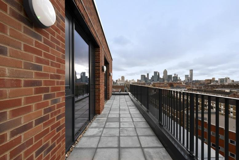 Spacious rooftop terrace at Lock Studios featuring brick walls and views of the London skyline.