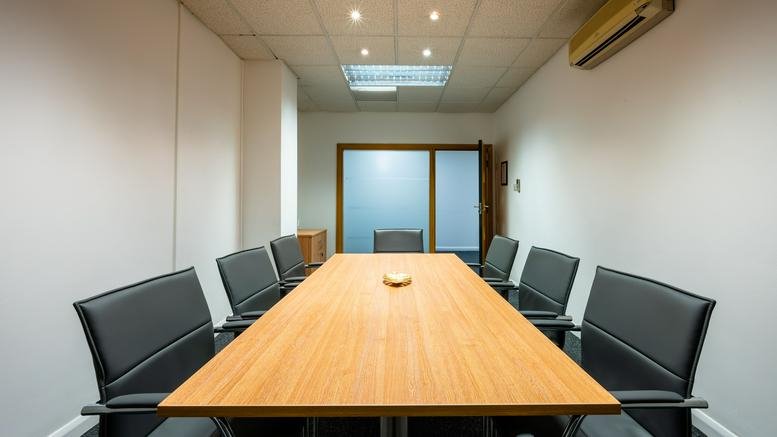 Spacious boardroom at Lonsdale House, 52 Blucher Street featuring a long wooden table and black leather chairs.