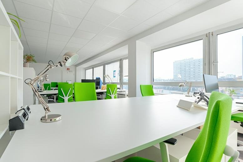 Spacious open-plan workspace at Mörfelder Landstraße 6-8 with bright green chairs and natural light.