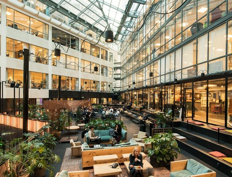 Spacious sun-drenched atrium at Mäster Samuelsgatan 36, Stockholm with lounge seating and plants.