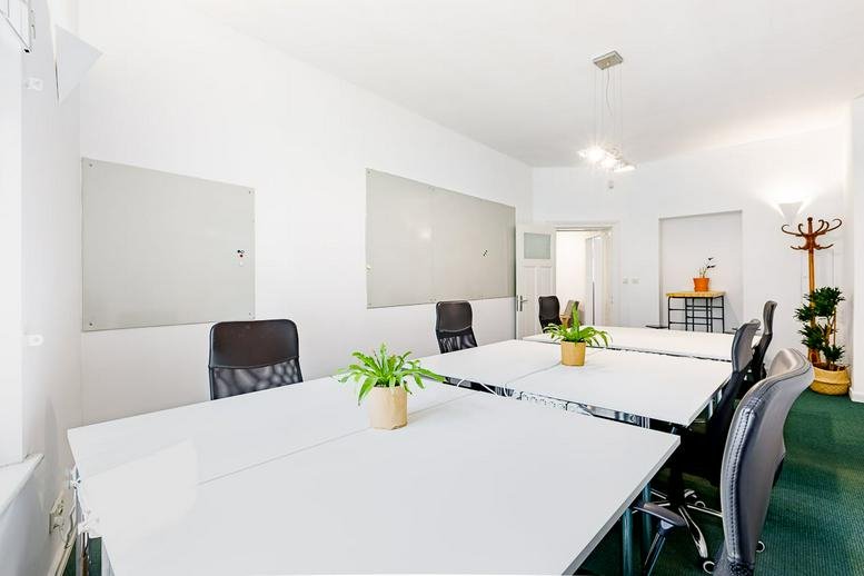 Spacious shared workspace with multiple workstations and a modern coat rack.