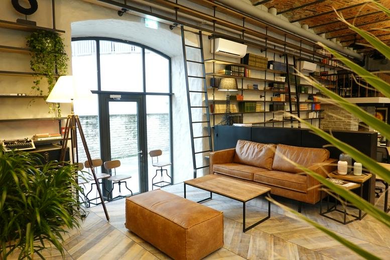 Spacious communal lounge at Maakri 25, Tallinn, Estonia with a leather sofa, wooden coffee table, and tall bookshelf.