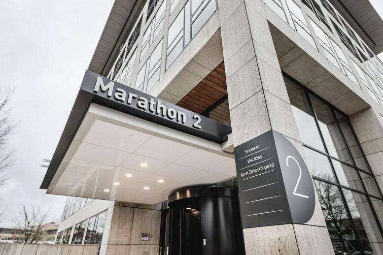 Exterior view of the modern glass and stone facade at Marathon 2, Hilversum, North Holland.