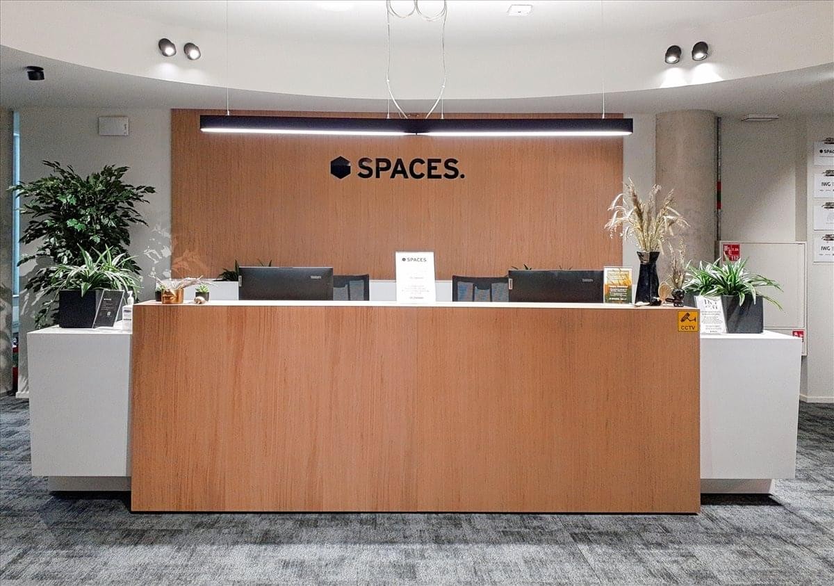 Modern reception area with a wood-paneled front desk and branded wall at Novira Plaza.