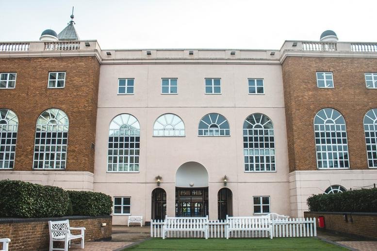 Exterior facade of Marina Studios, Harbour Yard, Chelsea Harbour, London featuring arched windows and white benches.