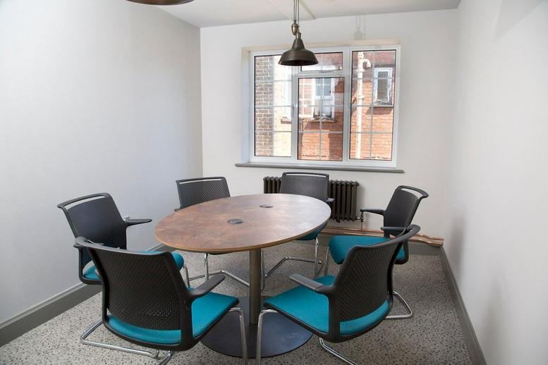 Meeting room with a central oval table under a vintage-style pendant light.