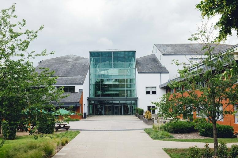 Exterior view of the glass-facade Marlow International building surrounded by lush greenery.