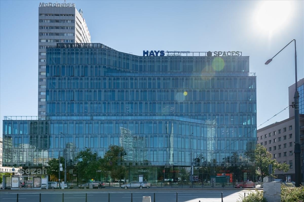 Modern glass-facade exterior of the Marszalkowska Centre under a bright blue sky.