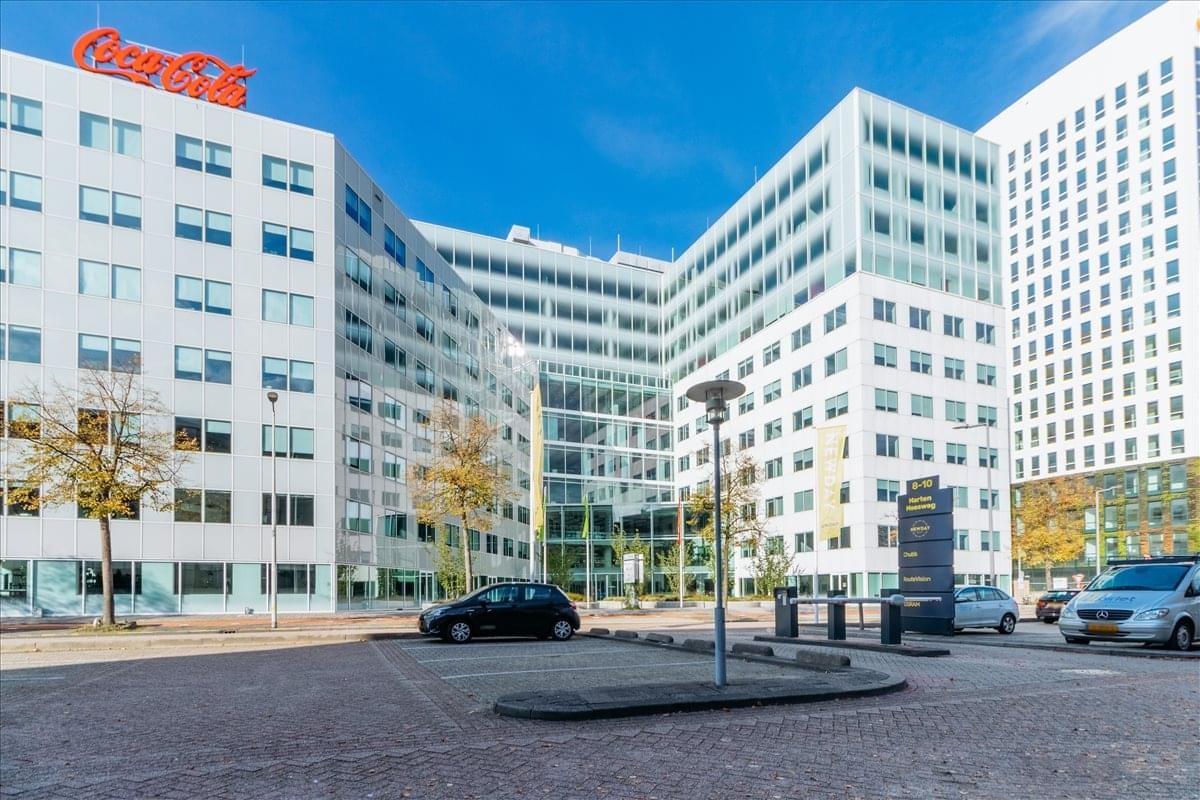 Exterior view of the modern white office building at Marten Meesweg 25-G with a clear blue sky.