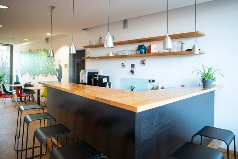 Modern kitchen and bar area with hanging pendant lights and wooden shelves.
