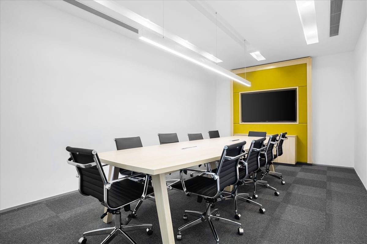 Meeting room at Maslak Orjin Business Centre with a long light-wood table and yellow feature wall.
