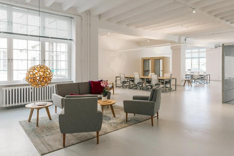 Spacious sunlit lounge area at Mehringdamm 32-34, Berlin, Brandenburg with grey armchairs and a designer pendant light.