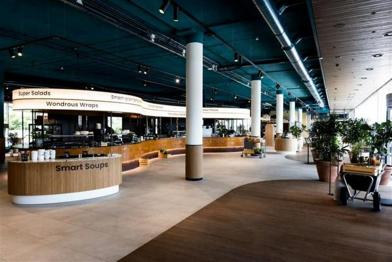 Spacious communal cafe area with a long curved service counter and teal ceiling at Mercuriusplein 1, Hoofddorp.