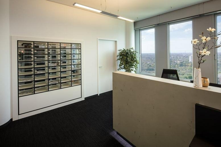 Professional reception area at Mergenthalerallee 10-12 featuring a stone desk and digital mailboxes.