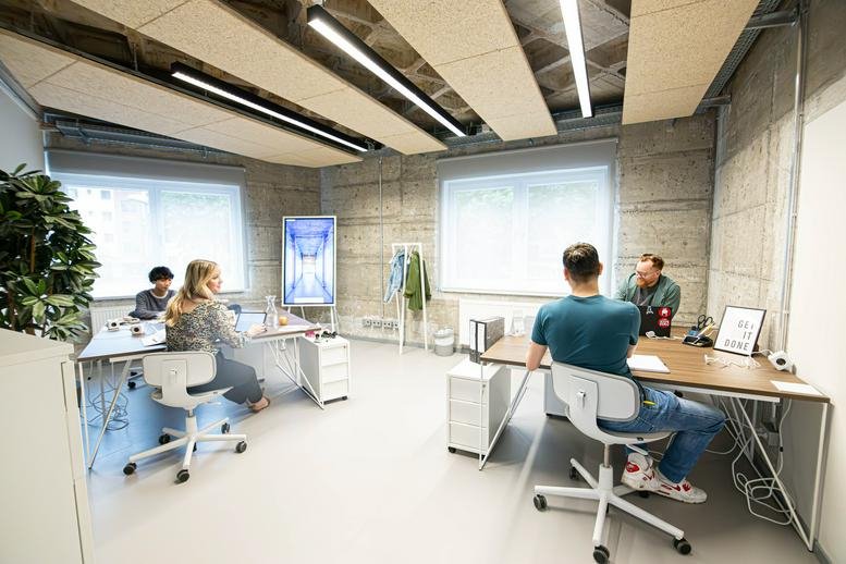 Spacious open office with concrete walls and modern industrial lighting.