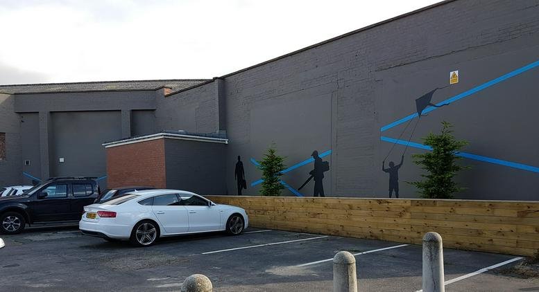 Exterior facade of the Microfirms Centre, 266-290 Wincolmlee, featuring a grey wall with creative silhouette murals.