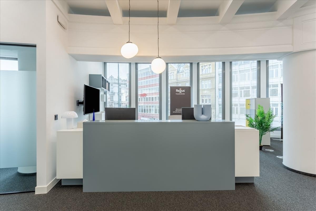 Modern reception desk at Mielzynskiego 14, Poznan with sleek grey finishes and hanging globe lights.