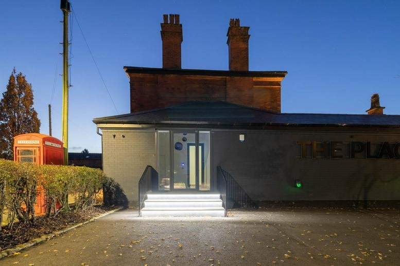 The main entrance of the Mill Lane building at twilight with illuminated steps and a red phone box.