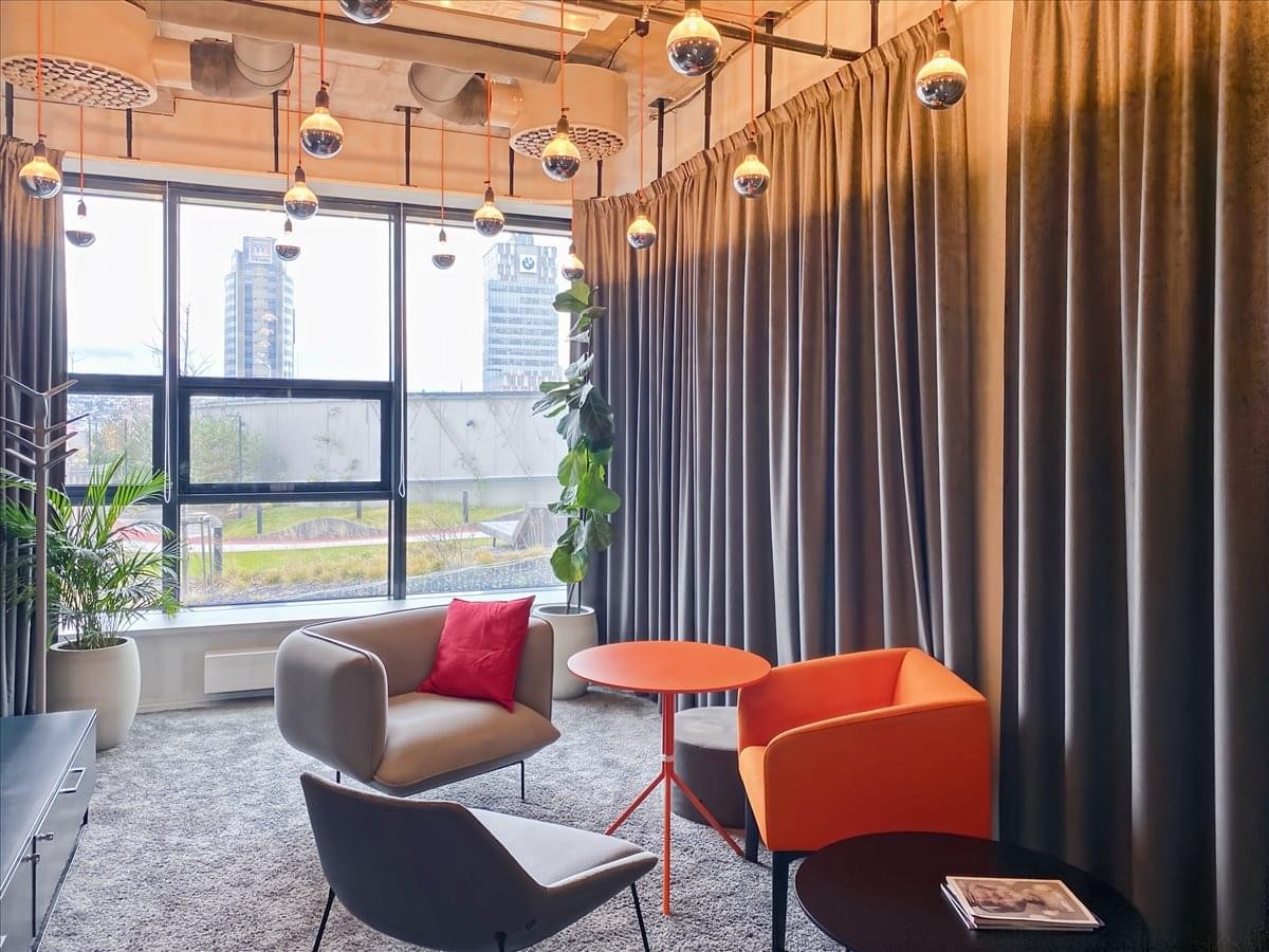 Colorful lounge area at Nivy Tower with pendant lights and floor-to-ceiling windows.