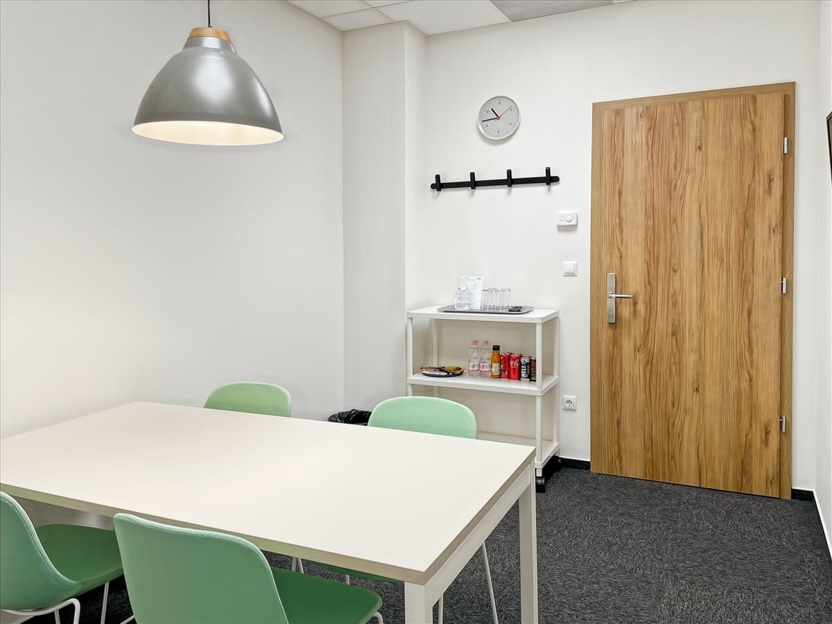 Professional meeting room at Montevideó Utca 9 with a white table and green chairs under a large pendant lamp.