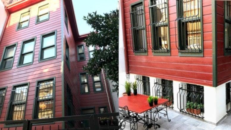 Exterior of the red timber-clad Kamara Altunizade Building with a patio and outdoor seating area.