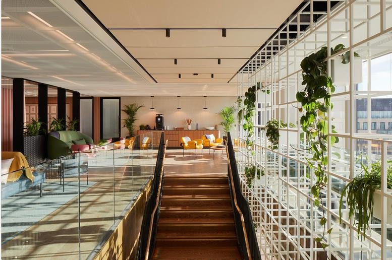 Spacious reception and lounge at Myo, Dashwood, 69 Old Broad Street with plants and wooden stairs.