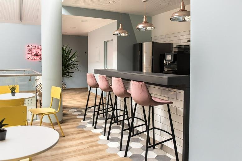 Spacious communal breakout area at Naugarduko gatvė 3, Vilnius featuring a modern cafe bar and pink velvet stools.