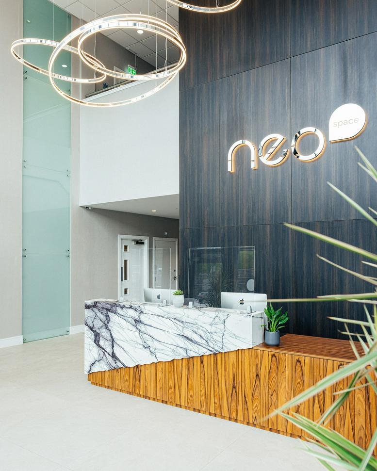 Modern reception desk at Neo house with marble finish and wood panelling.