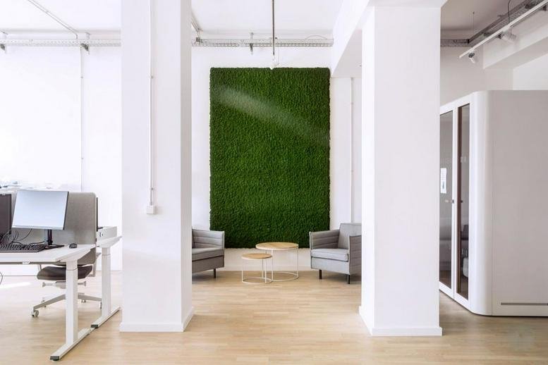 Spacious lounge at Neue Grunstrasse 17 with a vibrant moss feature wall and grey armchairs.
