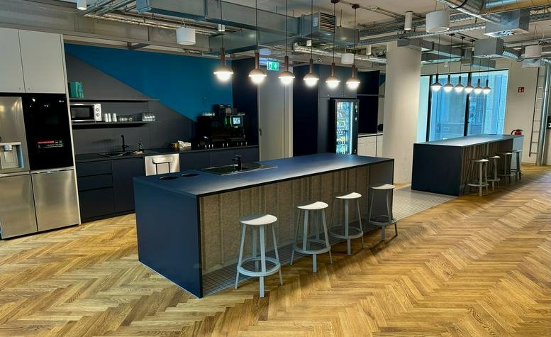 Spacious communal kitchen and lounge at Neue Rothofstraße 13-19 with wooden floors and blue feature wall.