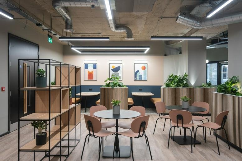 Spacious communal breakout area at Portland House with modern seating, dining tables, and indoor plants.