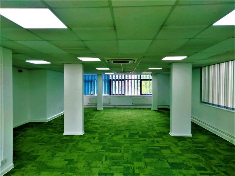 Spacious open-plan office space at Ramsden House with green carpet and large windows.