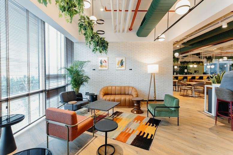 Spacious sunlit lounge at Nida Kule Ataşehir featuring mid-century furniture and vibrant potted plants.