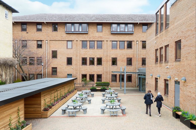 The brick exterior and courtyard of Nine Hills Road, Cambridge, Cambridgeshire with outdoor seating.