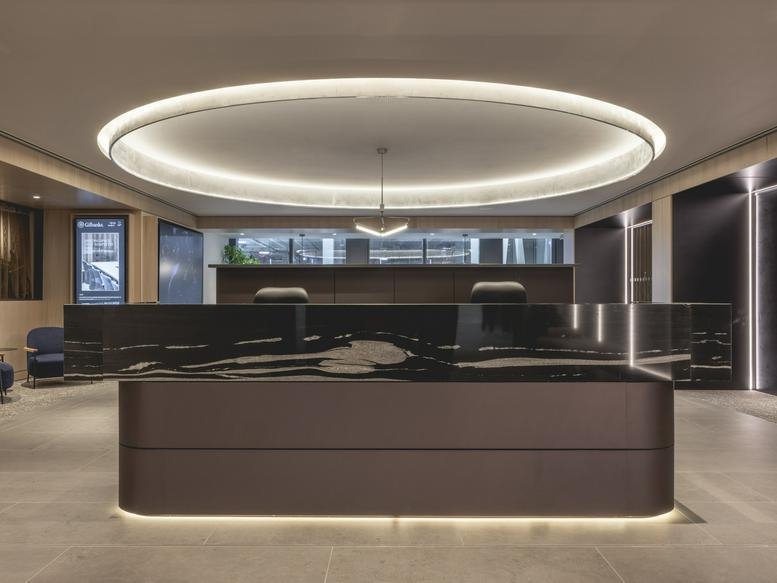 Sleek, modern reception area at No. 1 St Michael's with a dark marble desk and large circular halo ceiling light.