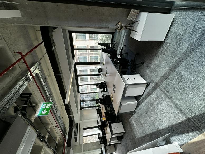 Long open-plan office suite with rows of desks and industrial ceiling details.