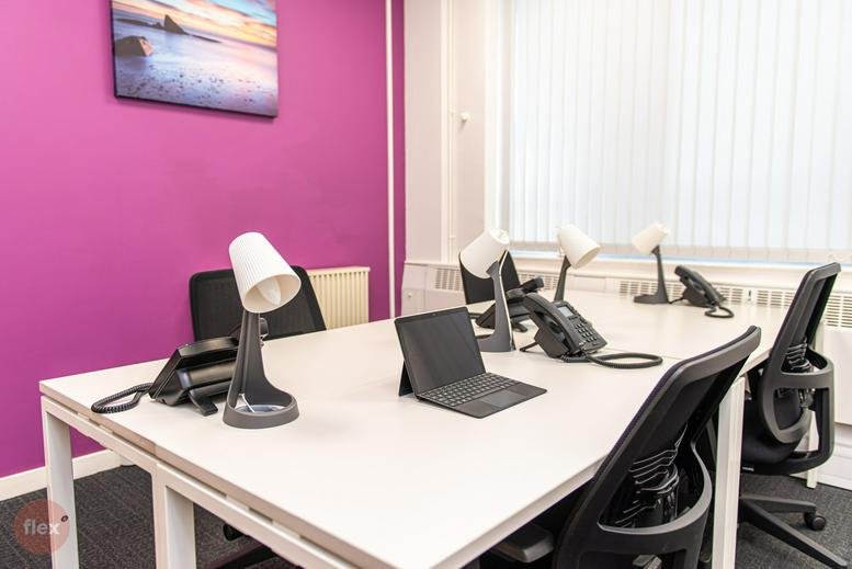 A modern meeting room at Norwich House, Dock Street, Hull with white desks and a pink feature wall.