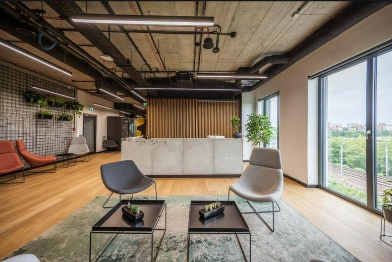 Modern reception area at O3 Business Campus with a concrete desk and minimalist grey armchairs.
