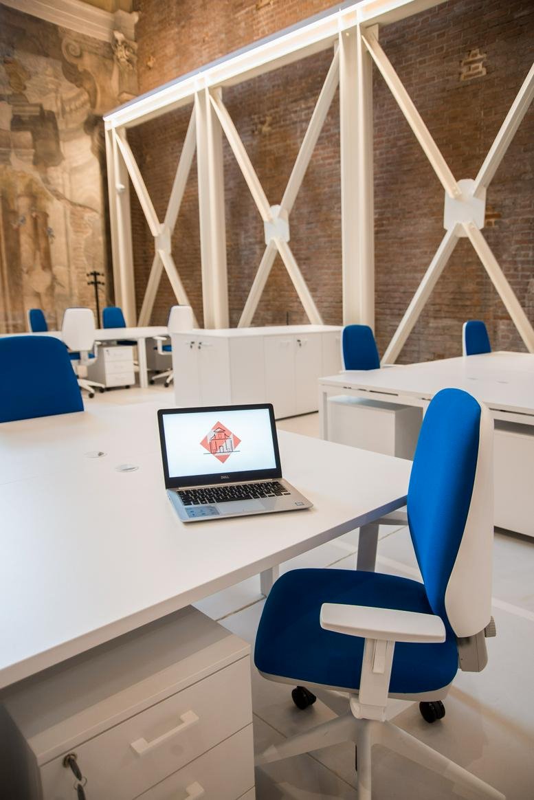 Modern desk area with blue ergonomic chairs and structural white support beams.