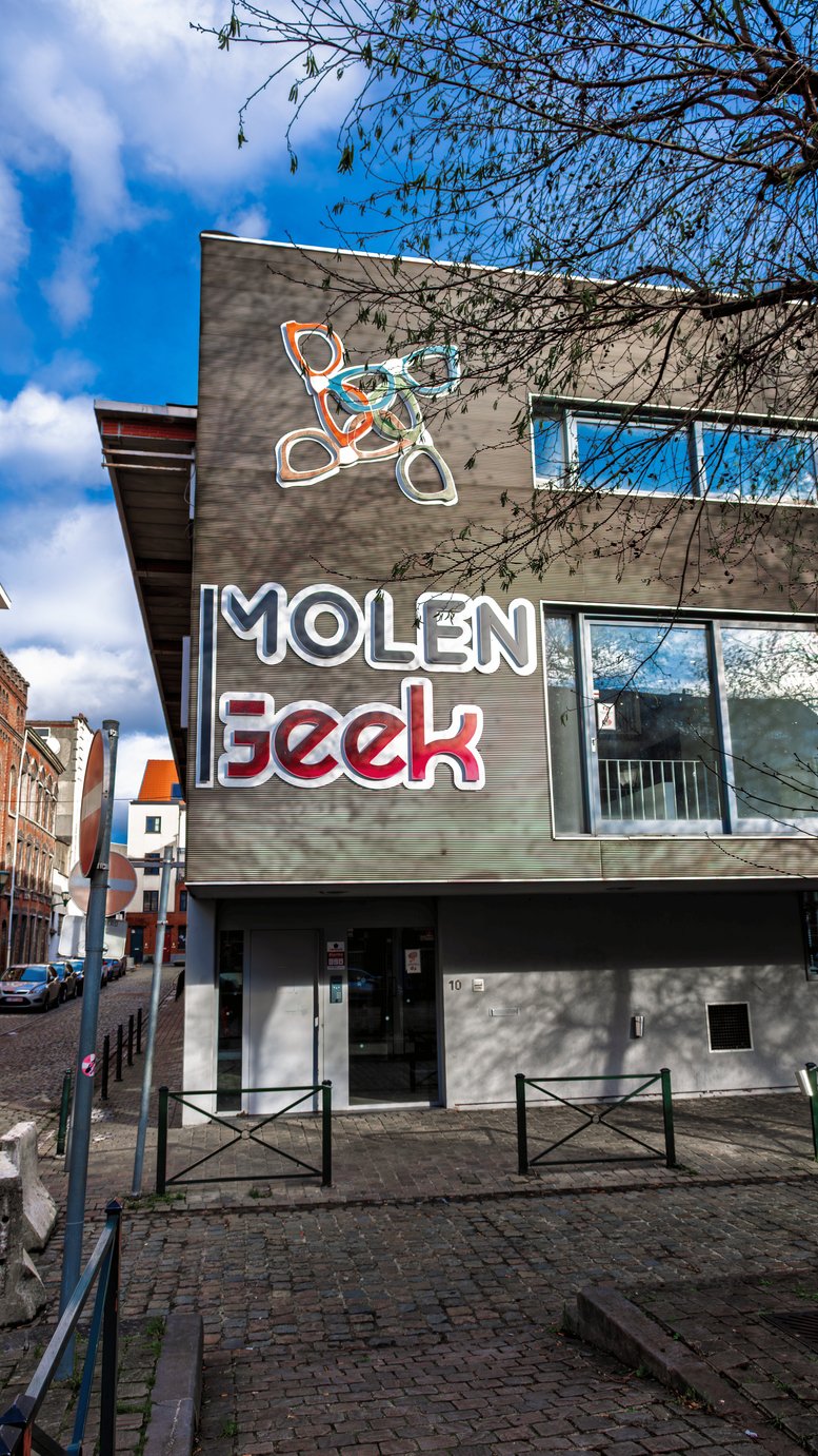 Portrait view of the contemporary facade at SideGeek Brussels featuring creative signage and abstract window art.